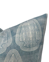 Close-up of a lake blue pillow cover with large, symmetrical white geometric and floral patterns and a distressed textured fabric appearance.