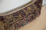 Rectangular pillow featuring a vintage rug fragment with intricate patterns in beige, burgundy, and dark blue on a neutral-toned surface.