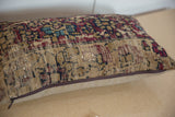 Rectangular pillow with a vintage-style rug pattern featuring muted red, navy, beige, and blue colors, resting on a light wooden surface.