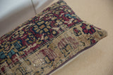 Rectangular pillow featuring a vintage rug fragment pattern with intricate geometric shapes in muted red, blue, and beige tones, resting on a neutral surface.