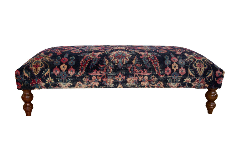 Vintage Persian rug ottoman coffee table showing navy and faded magenta rug fragment on curved wooden legs