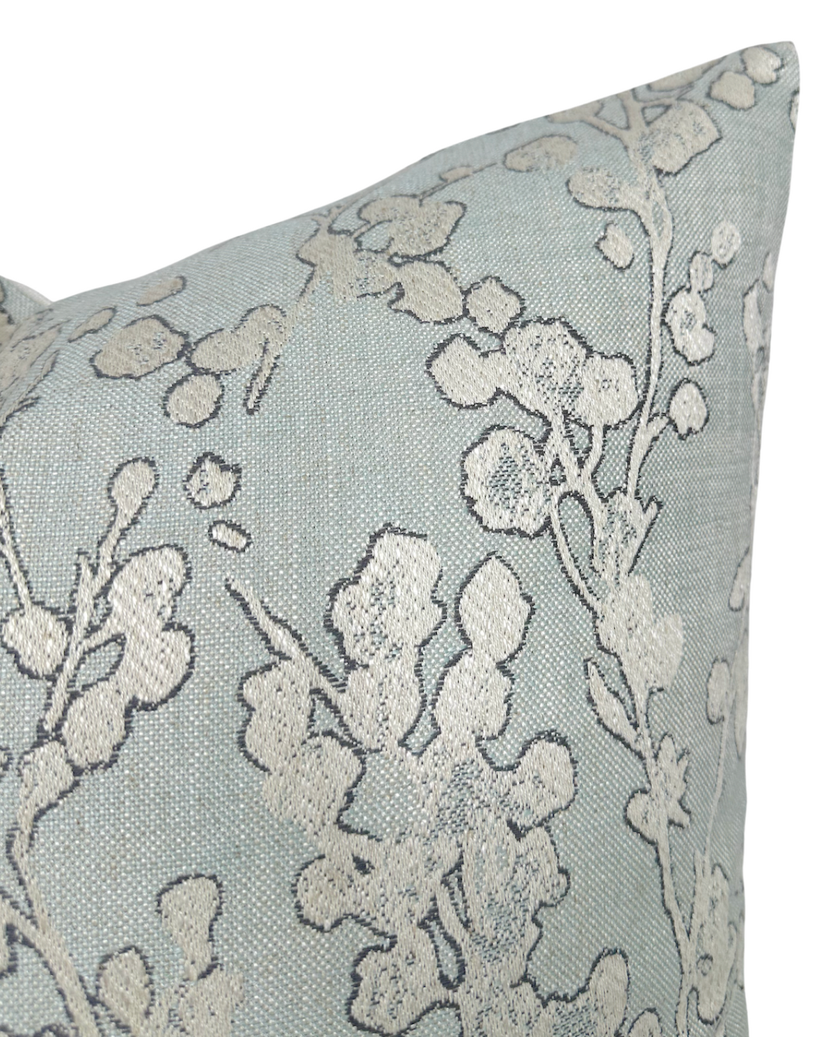 Light blue pillow cover with textured cream floral and eucalyptus leaf pattern in a close-up view