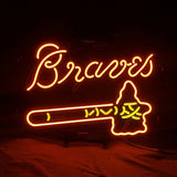 Bright orange neon sign spelling 'Braves' above a tomahawk outline with yellow details on a dark background