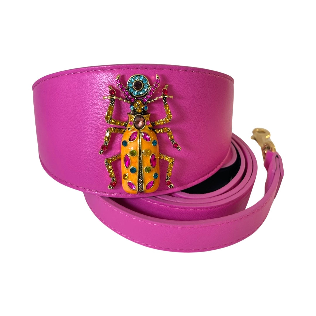 Bright pink belt featuring a large decorative beetle embellishment with yellow, red, green, and blue jeweled details and a gold clasp.