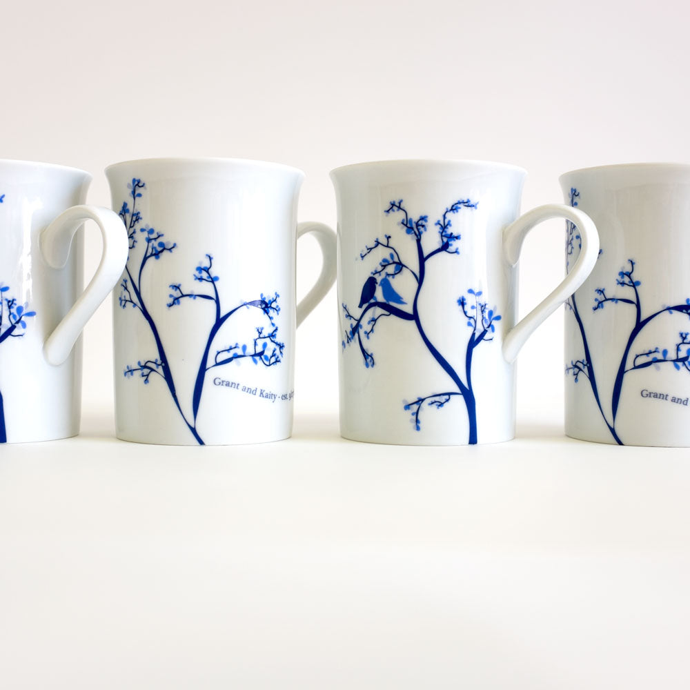 Set of four personalized Love Bird Mugs in chocolate and cobalt colors arranged side by side