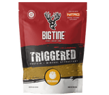 Red and black Big Tine Triggered Persimmon attractant bag featuring a white deer head logo and orange persimmon icon, standing upright against a green background