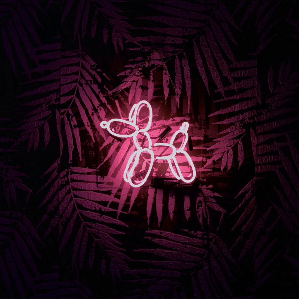 Pink neon light shaped like a balloon dog mounted on a dark wall with a purple tropical palm leaf pattern in the background.