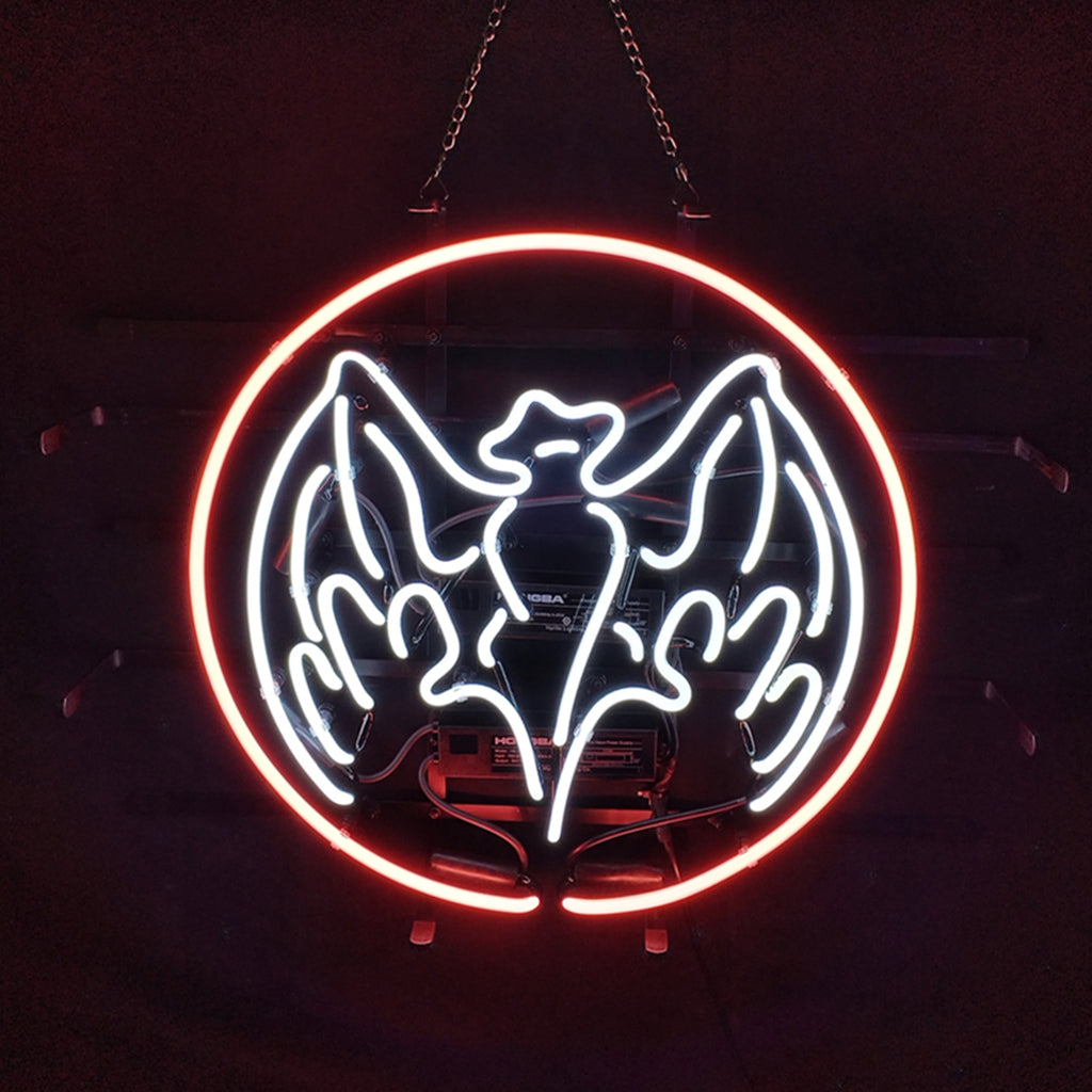 Bat-shaped neon sign glowing orange mounted against a dark background