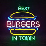 Neon sign showing a yellow burger bun outline with pink letters spelling BURGERS and green text reading BEST above and IN TOWN below, with blue decorative lines.