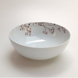 White ceramic bowl with delicate brown botanical branch and heart designs along the inner rim, shown on a plain light background.