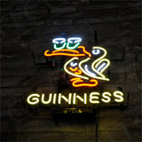 Neon sign featuring a stylized white toucan with an orange beak perched above two glowing beer pints, with 'GUINNESS' written below in yellow neon letters against a dark brick wall.
