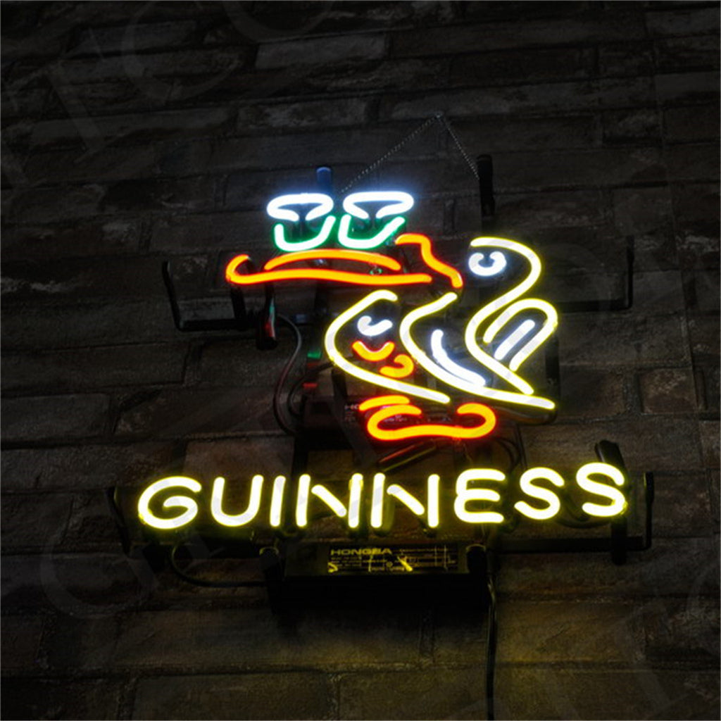 Neon sign featuring a stylized white toucan with an orange beak perched above two glowing beer pints, with 'GUINNESS' written below in yellow neon letters against a dark brick wall.