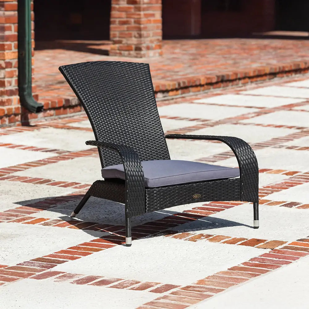 Black woven wicker lounge chair with curved arms and a gray seat cushion, positioned on a patterned brick and concrete patio outdoors.