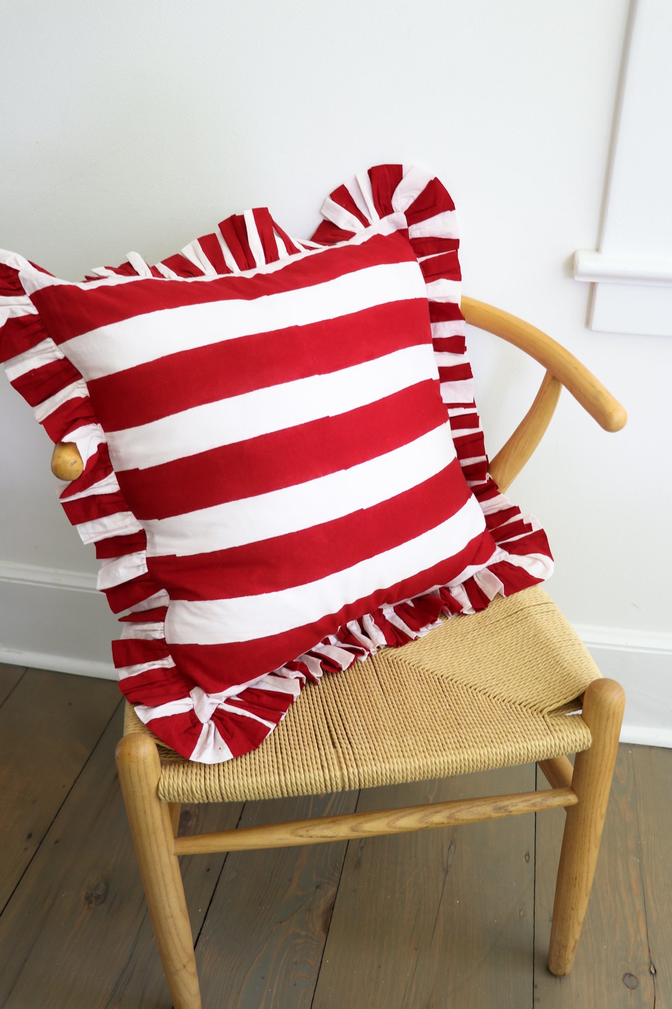 Ruffled Stripe Throw Pillow in cherry red with block-printed stripes and ruffled edges on a neutral cushion.
