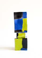 Stacked squared ceramic vase with bold color blocks in blue, yellow, and black arranged in an abstract pattern against a white background.