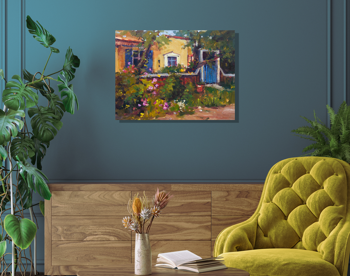 Impressionist-style painting of a yellow house with a blue gate and vibrant garden flowers, displayed on a teal wall above a wooden sideboard and mustard green chair.