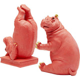Two pink hippopotamus bookends with gold-colored details on ears and toes, one sitting upright and the other upside down on a rectangular base.