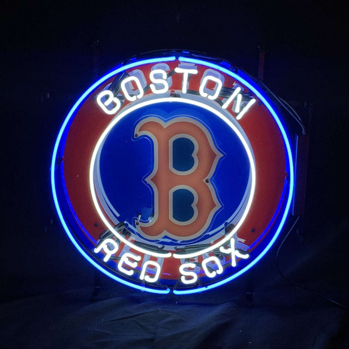 Circular Boston Red Sox logo neon sign with red B on blue background, surrounded by white text 'BOSTON' above and 'RED SOX' below, outlined in blue neon.