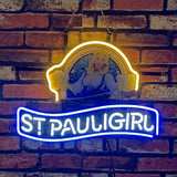 Neon sign with bright blue 'ST PAULI GIRL' text below a yellow-glowing figure of a smiling woman in traditional dress holding two beer mugs, mounted on a brick wall.