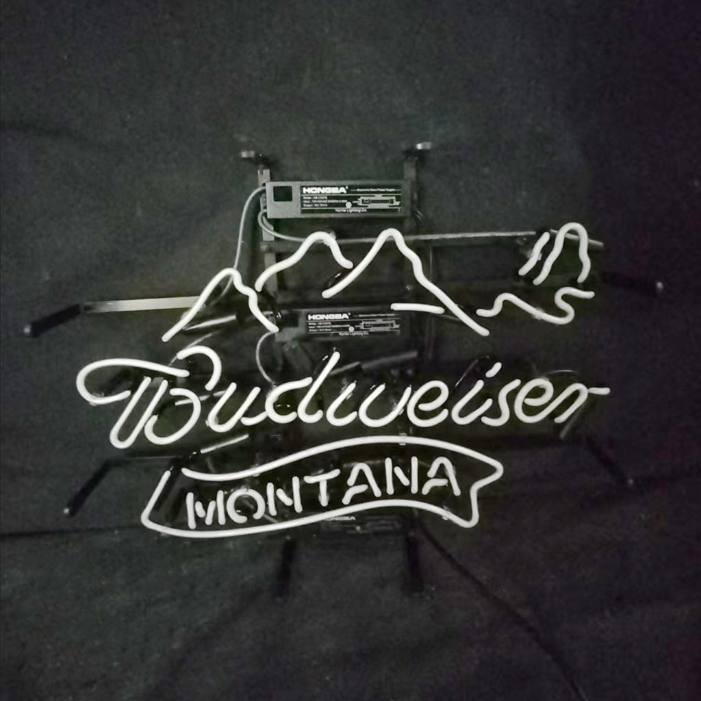 White neon light sign with a mountain outline above cursive 'Budweiser' and block letters spelling 'Montana' beneath on a dark background