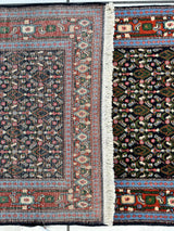 Close-up of a vintage Persian Senneh runner rug showing intricate geometric and floral patterns in muted reds, blues, and creams with a white fringe separating two different patterned sections.