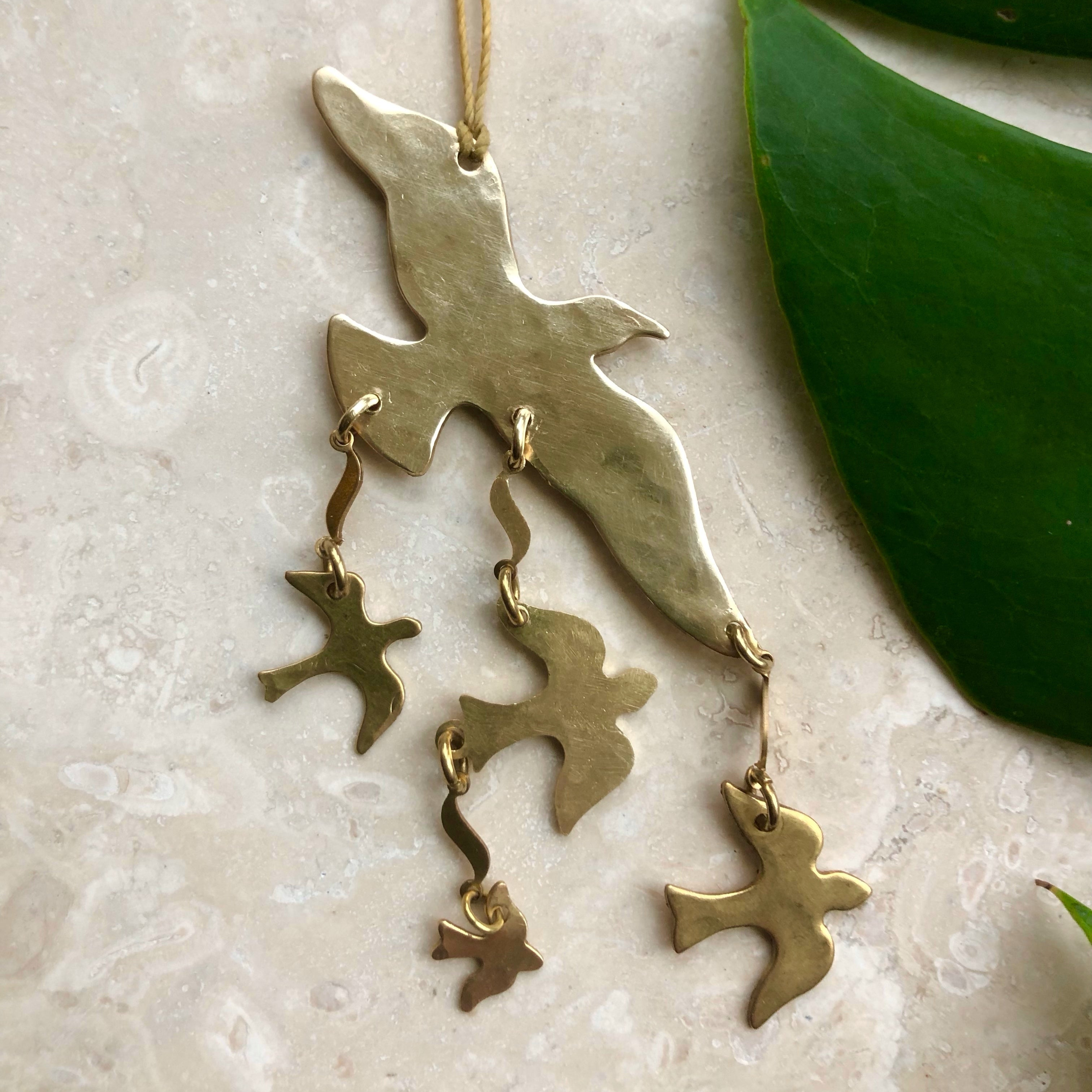 Birds of a Feather Ornament hand-cut and hammered brass wall hanging with thin cord, displayed on white background