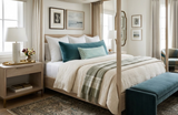 Neutral-toned bedroom with a white four-poster bed featuring green and teal pillows, light wood side tables, beige curtains, and a teal bench at the foot of the bed.