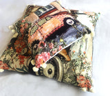 Two square decorative throw pillows featuring vintage car and floral prints with soft pom-pom trim, layered on a light background.