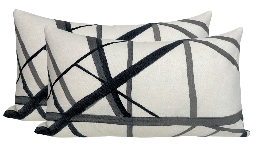 Two rectangular white pillow covers with intersecting black and gray diagonal lines creating a modern geometric pattern.