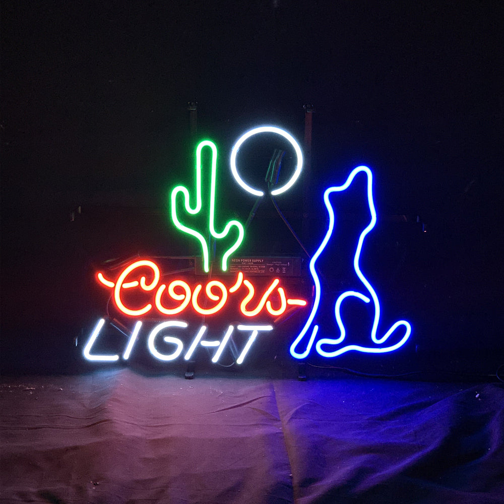 Neon sign depicting cactus, moon, wolf, coyote, and Coors Light beer on a metal grid backing illuminated indoors