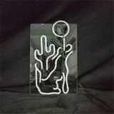 Clear rectangular panel with white neon tubing shaped like a cactus and a glowing circle above it, set against a dark background.