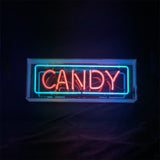 Rectangular neon sign with the word CANDY in bright red letters outlined by a teal-blue rectangular border, all against a black background.
