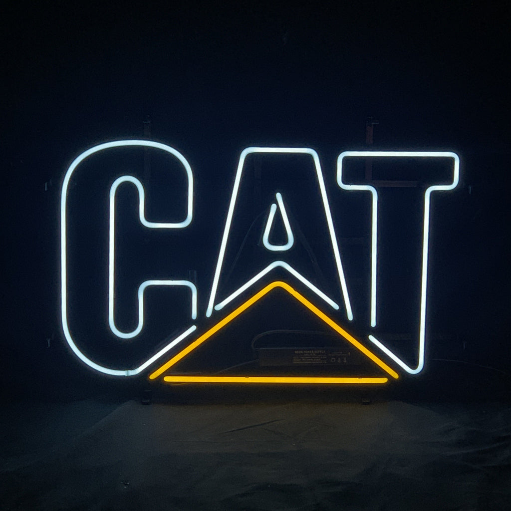 Neon sign displaying the word 'CAT' with white letters and a yellow triangle beneath the 'A' on a black background