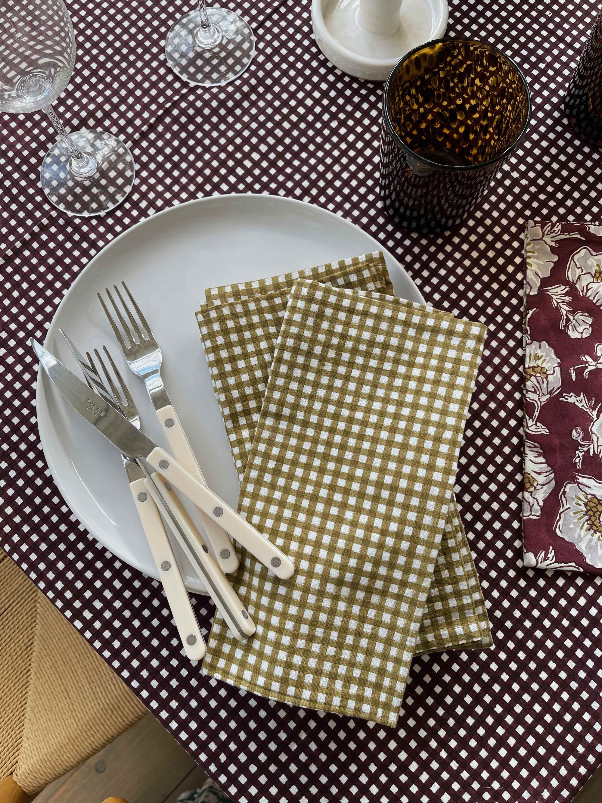 Set of six chartreuse and mustard gingham napkins stacked with a textured background
