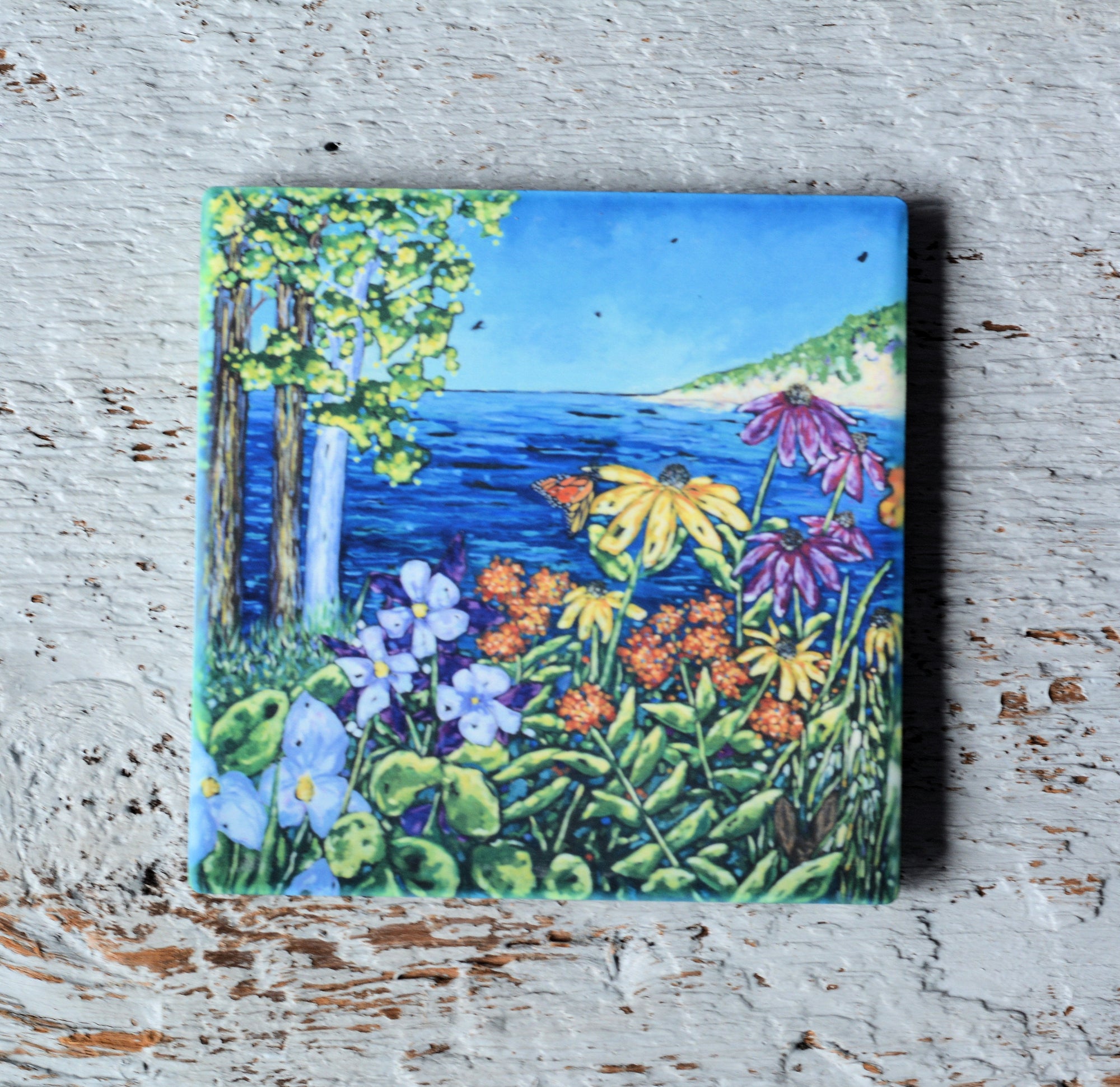 Coasters featuring colorful artwork by Christi Dreese on a light surface