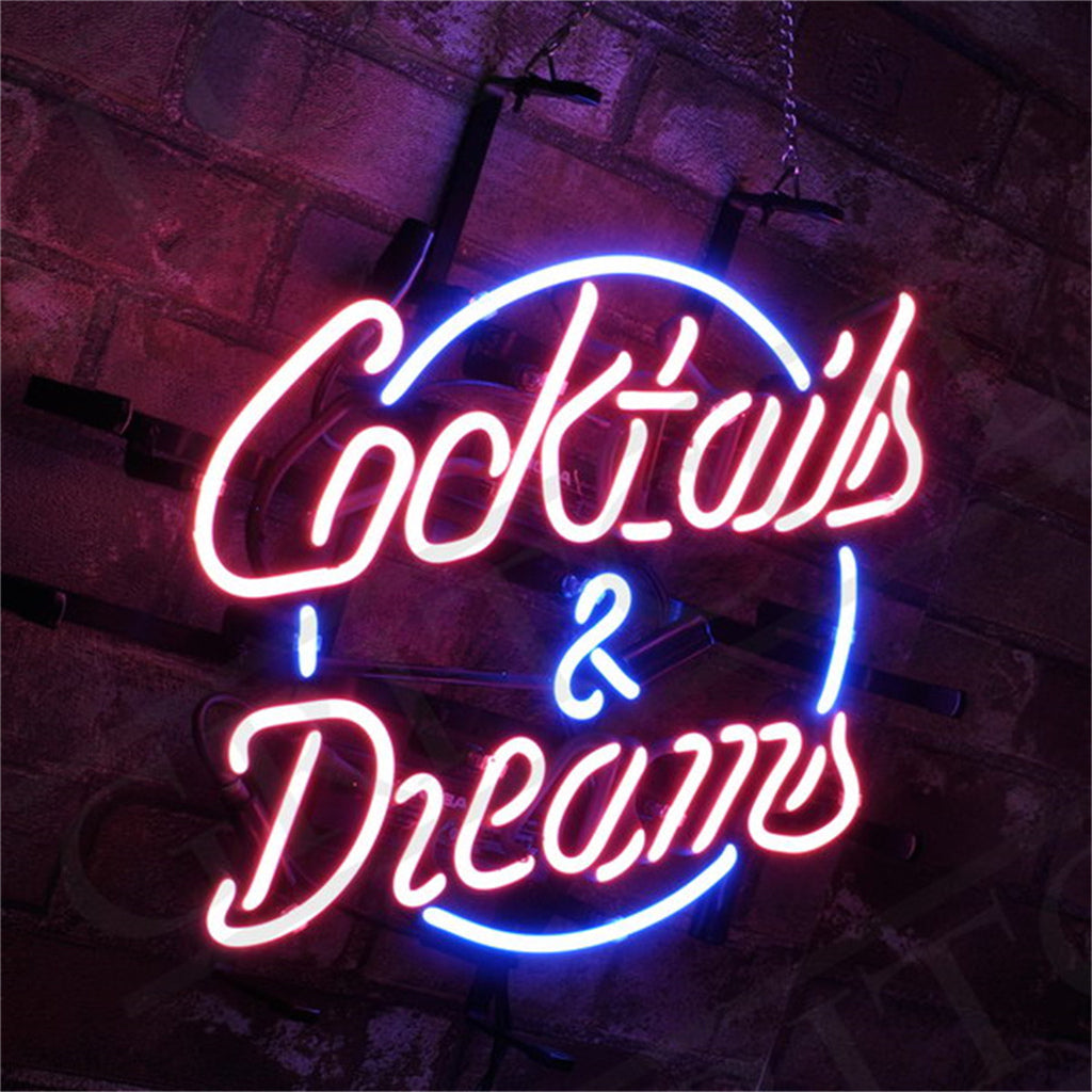 Neon sign with pink cursive text reading 'Cocktails & Dreams' surrounded by a blue circular outline against a dark brick wall background.