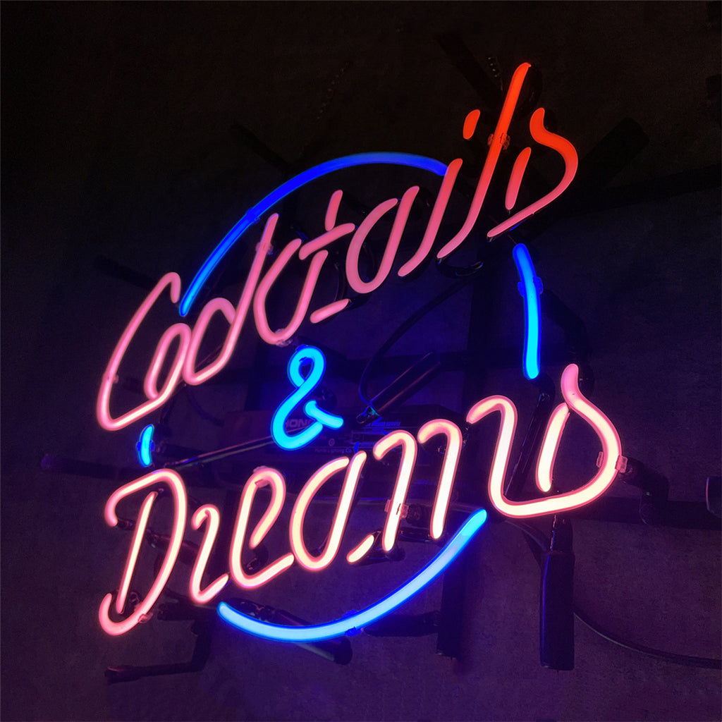 Neon sign with pink cursive text reading 'Cocktails & Dreams' inside a blue circular outline, glowing against a dark background.