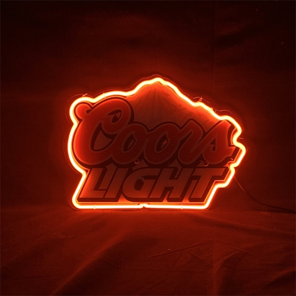 Coors Light logo outlined with bright red neon light glowing against a dark background highlighting bold cursive and block lettering.