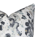 Close-up of a velvet pillow cover with an abstract, mottled pattern in black, gray, and beige on a white background
