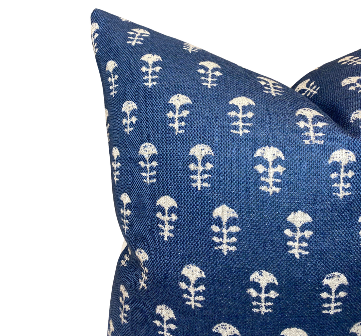 Close-up of a blue woven pillow cover featuring a repeating white floral motif with a textured fabric surface.