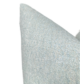 Close-up of a light blue boucle pillow cover with a textured, looped fabric surface, shown against a white background.