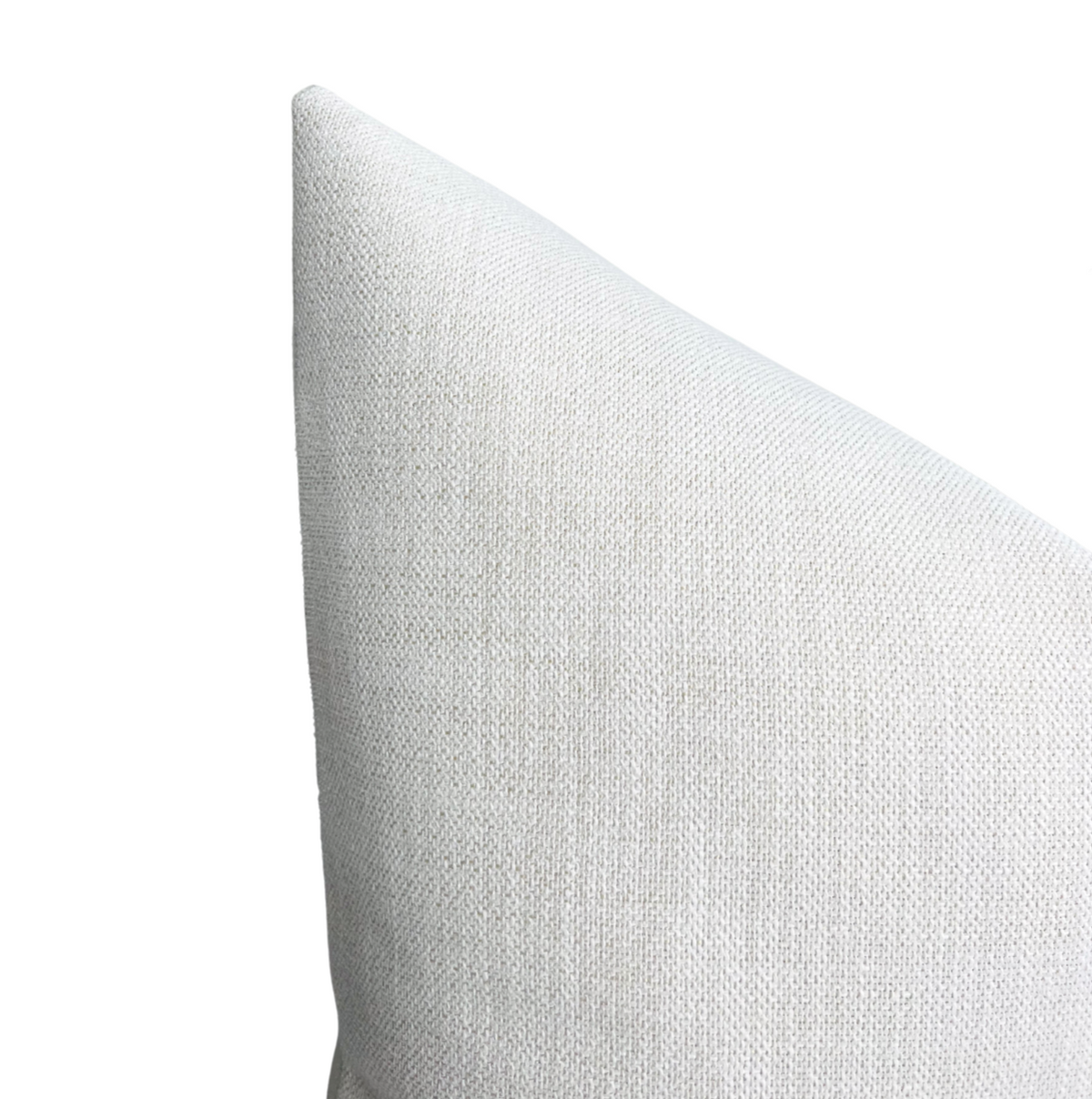 Close-up of a triangular corner of a chalk-colored woven outdoor pillow cover with a textured fabric surface.