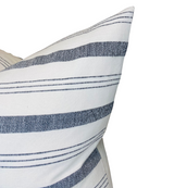 Close-up of a pillow cover featuring natural fabric with alternating wide and thin horizontal navy blue stripes on a white background.