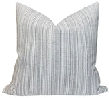 Veranda Strie Pillow Cover in Grey displayed on a cream sofa with a dark background