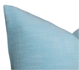 Close-up of a textured outdoor pillow cover in poolside blue with a woven fabric pattern showing interlaced light and medium blue threads.