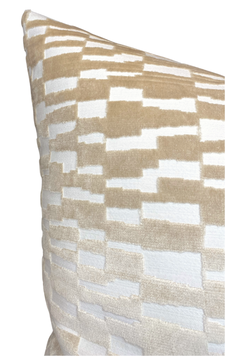 Close-up of a pillow corner featuring a tan brown and white geometric pattern with a soft velvet texture.