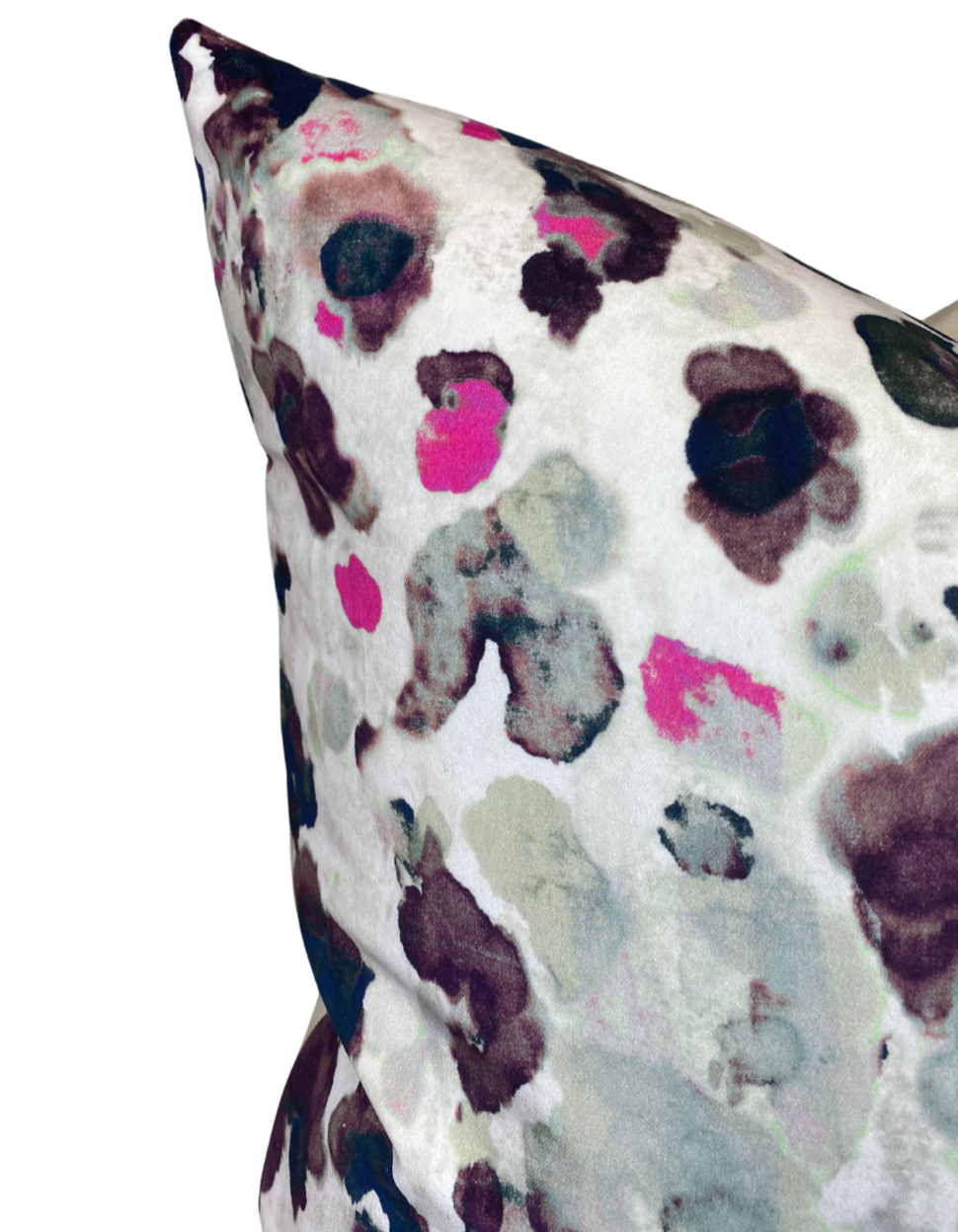 Close-up of a velvet pillow cover with an abstract floral pattern in pink, grey, black, and muted green on a white background