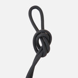 Black braided rope tied into a looped knot on a white background, showing texture and flexibility of the cord material.