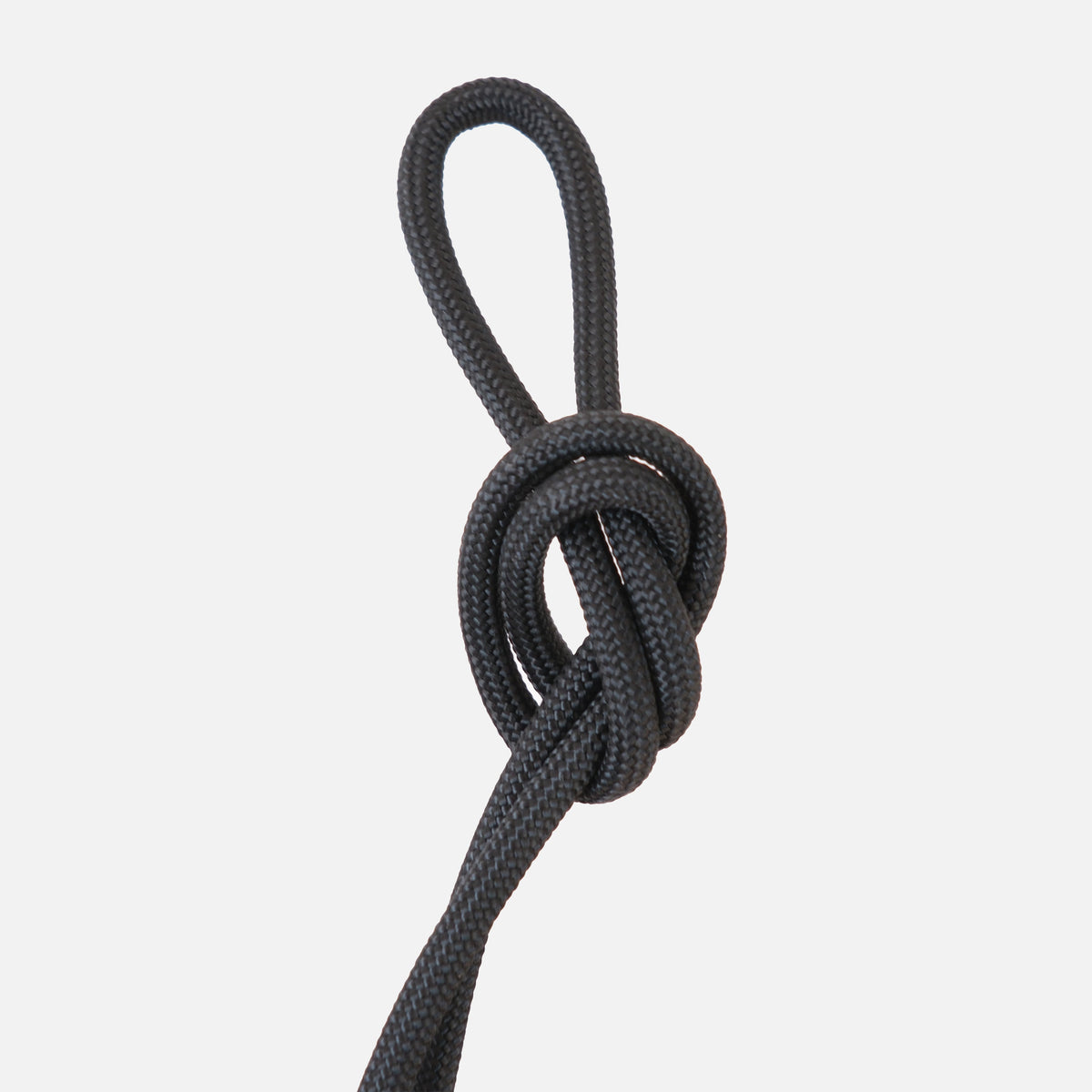 Black braided rope tied into a looped knot on a white background, showing texture and flexibility of the cord material.