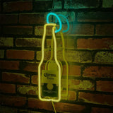 Yellow neon outline of a Corona Extra beer bottle with a blue neon lime slice above it, mounted on a red and brown brick wall, casting a shadow.